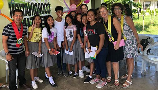 College officials pose for a photo with students and their teacher in the Philippines