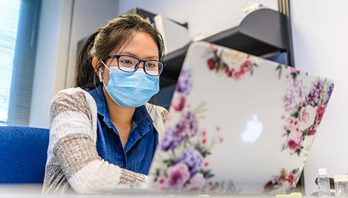 Female student with mask on laptop